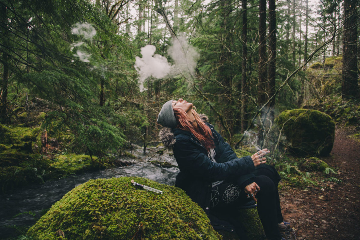 Millennial girl smoking cannabis while hiking in nature.